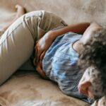 femme allongée tenant son ventre douloureux sans règles apparentes