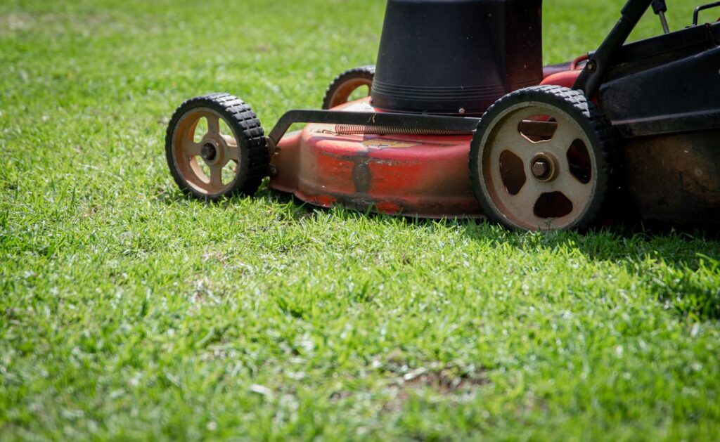 Tracteur-tondeuse Husqvarna rouge garé sur pelouse verte entretenue
