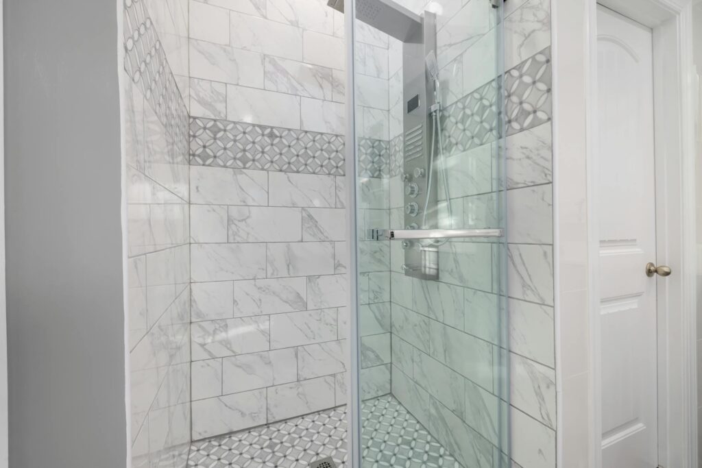Salle de bain rénovée avec carrelage clair, meuble épuré et robinetterie moderne
