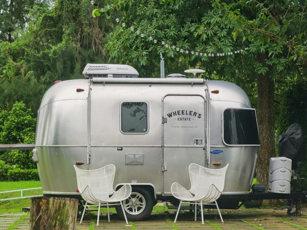 Tiny house en bois posée dans un jardin verdoyant, modèle compact sur remorque