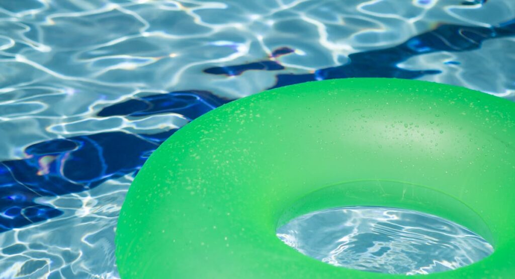 Main versant du chlore choc granulé dans une piscine extérieure ensoleillée
