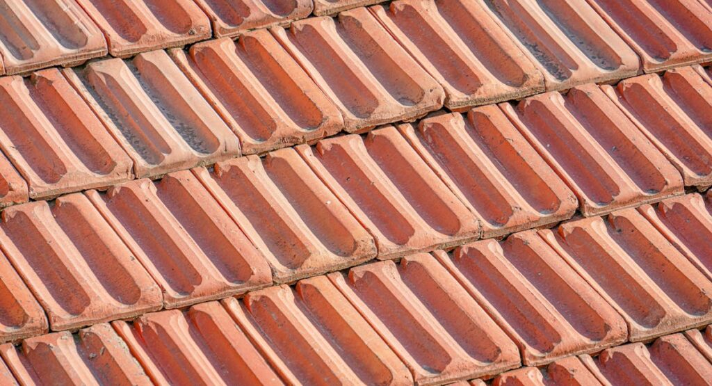Couvreur posant des tuiles en terre cuite sur une toiture en rénovation