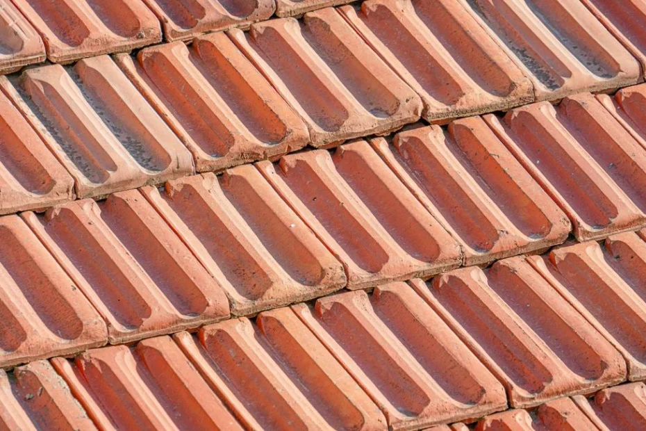 Couvreur installant un faîtage sur toiture avec tuiles rouges, ciel gris