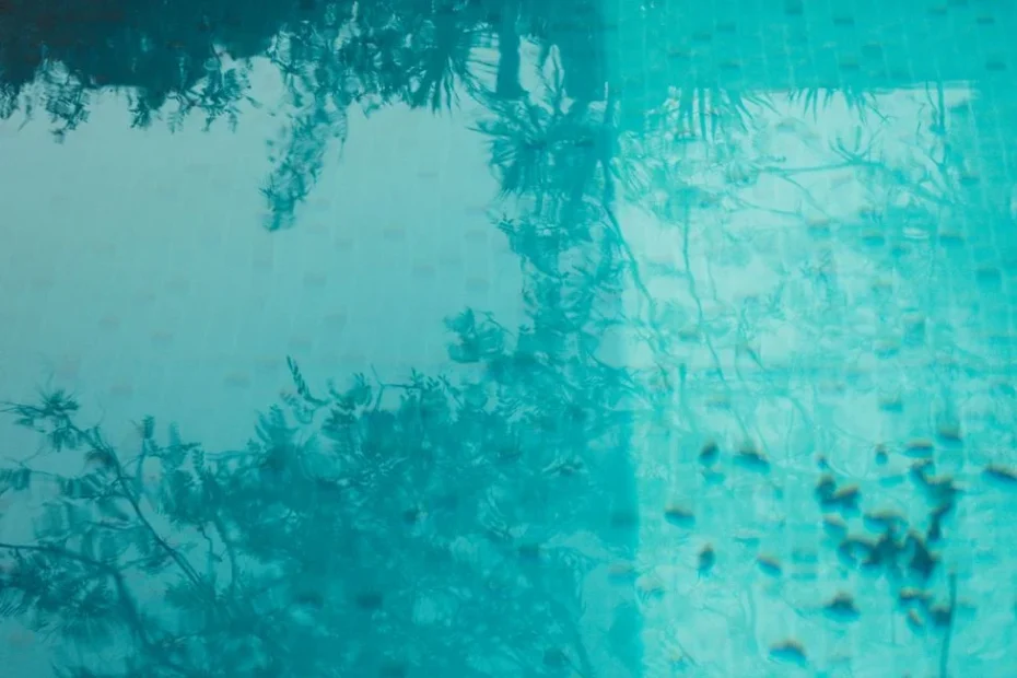 Eau de piscine trouble avec reflets verts sous soleil d’été et skimmer visible